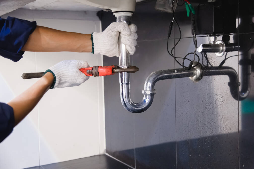 plumber fixing white sink pipe
